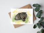 Card with a wombat illustration on a white background with a brown envelope and green leaves.